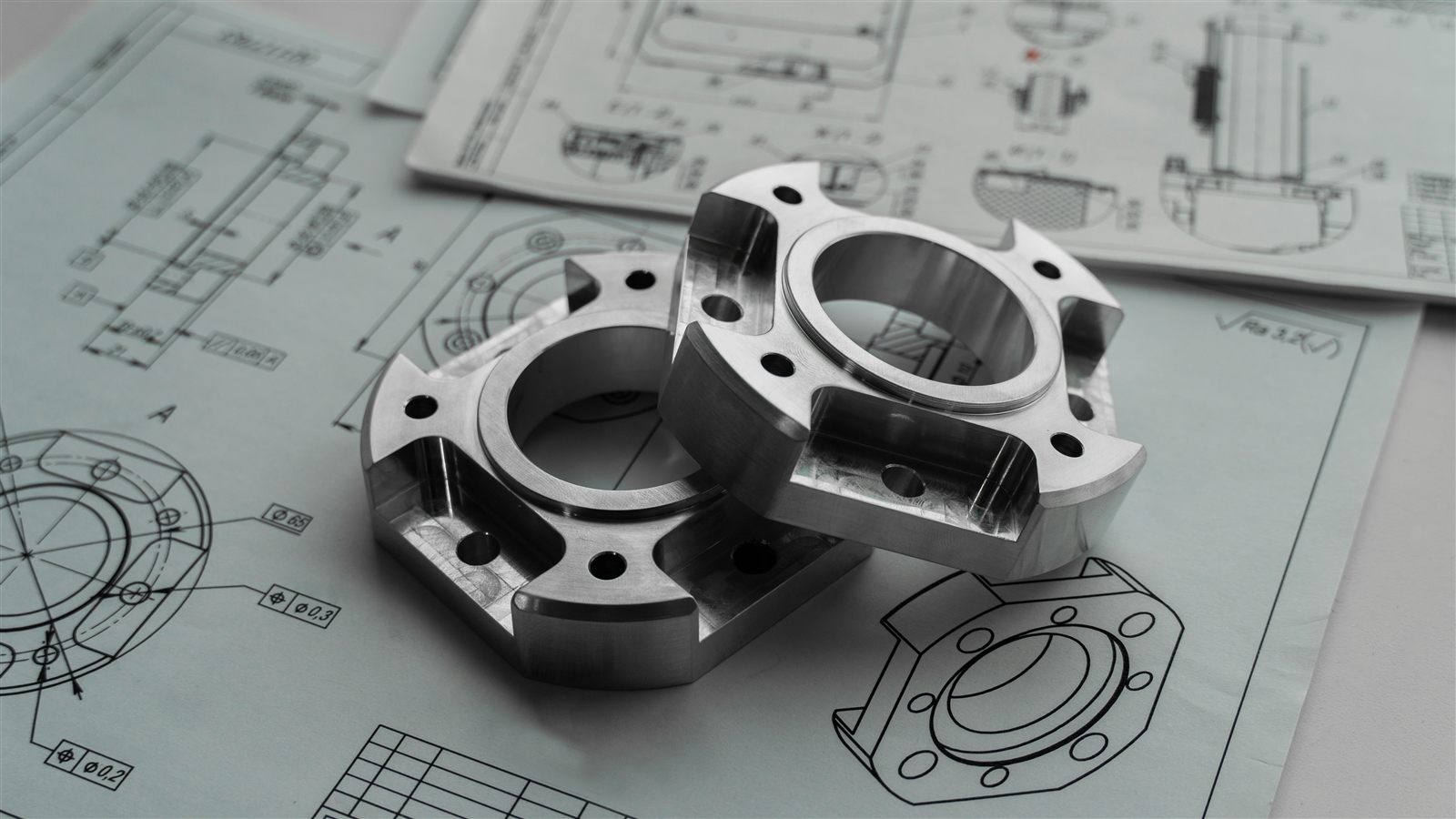 Precision-machined components resting on technical drawings